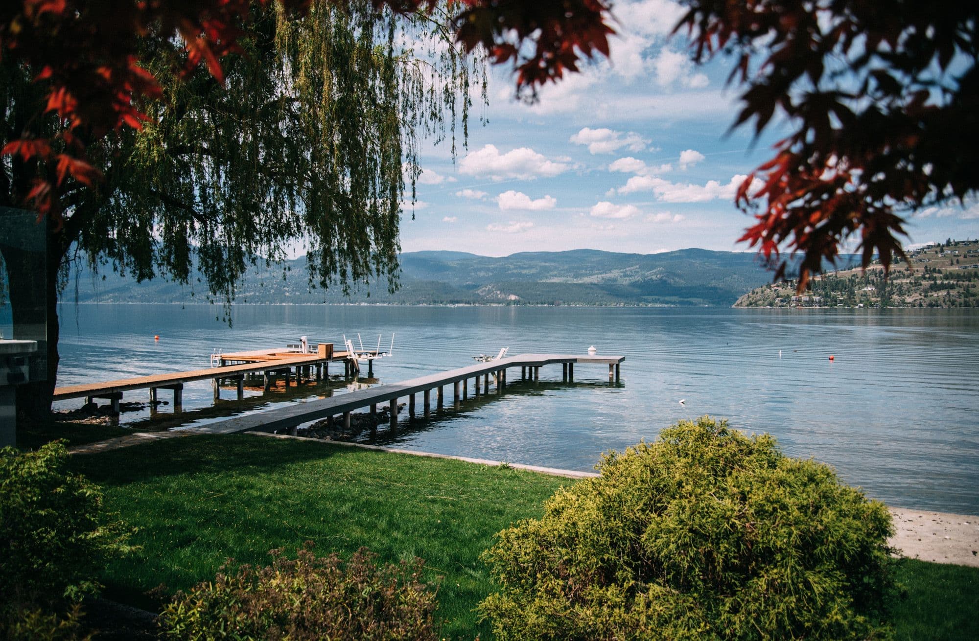 Classic wood-frame dock with dual walkways and boat lifts on Okanagan Lake in Vernon, BC, offering private lake access and scenic mountain views.