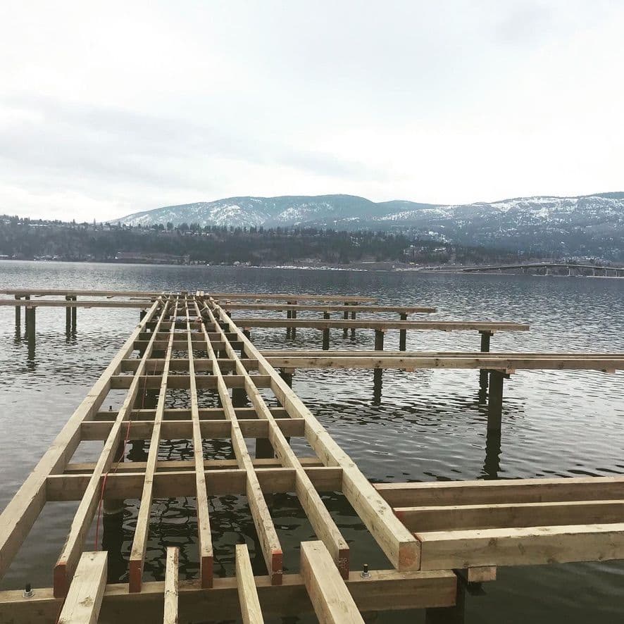 Framing in progress at Le Chateau Strata Marina in Kelowna, BC, highlighting steel piles and treated wood structure for full marina replacement and expansion.