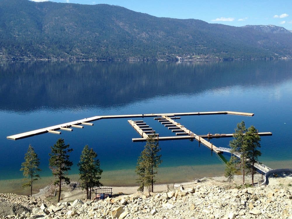 Panoramic scene of McKinley Beach Marina in Kelowna, BC, showcasing the floating steel dock system and surrounding lakefront terrain.