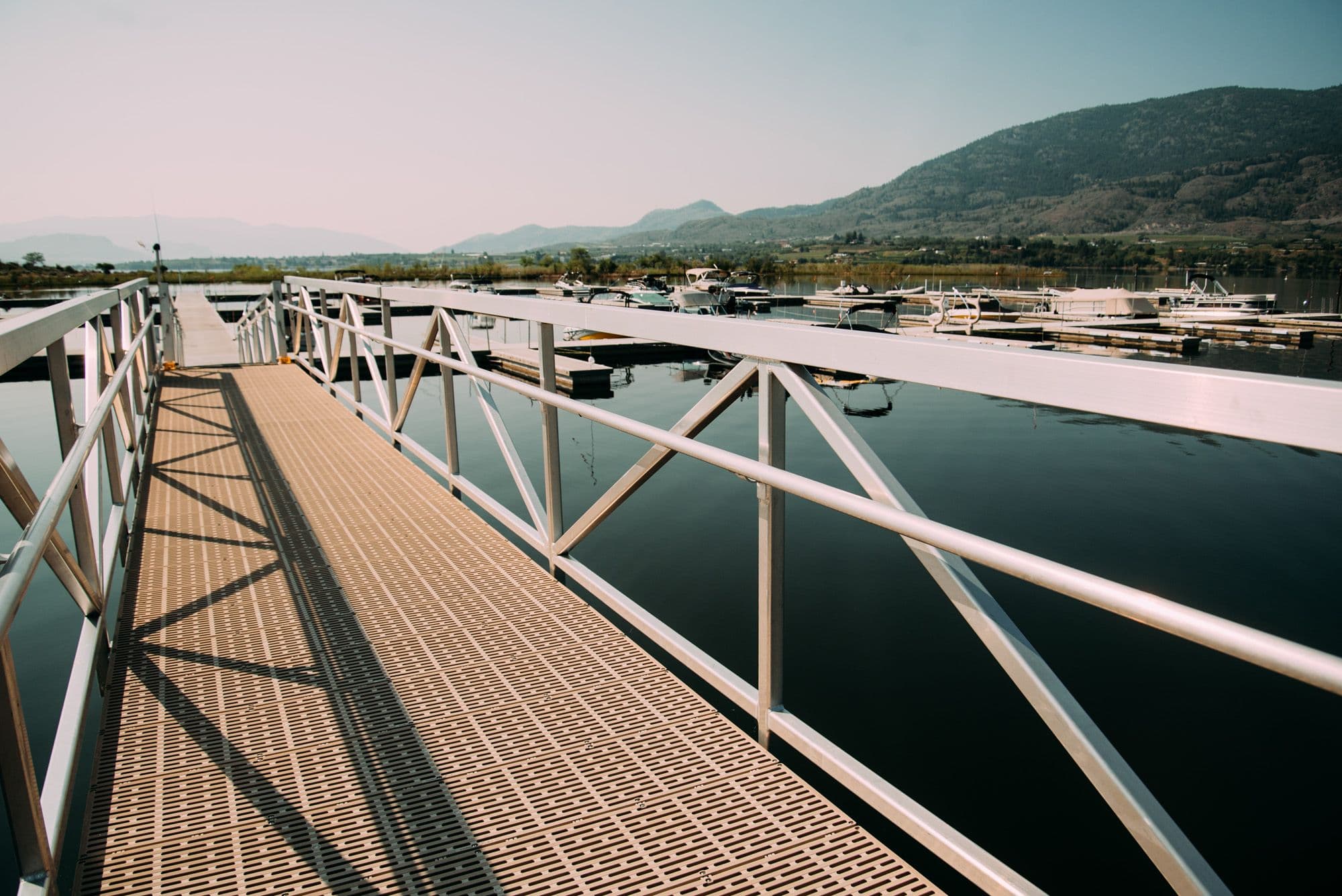 Close-up walkway shot at Osoyoos Cottages Marina with safety railings and steel gangway leading out to moorage slips.