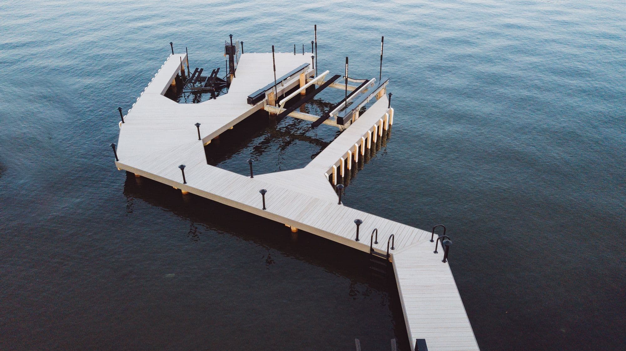 A custom-built residential dock on Okanagan Lake with multiple boat slips, mooring cleats, and a lounge area, designed for durability and functionality.