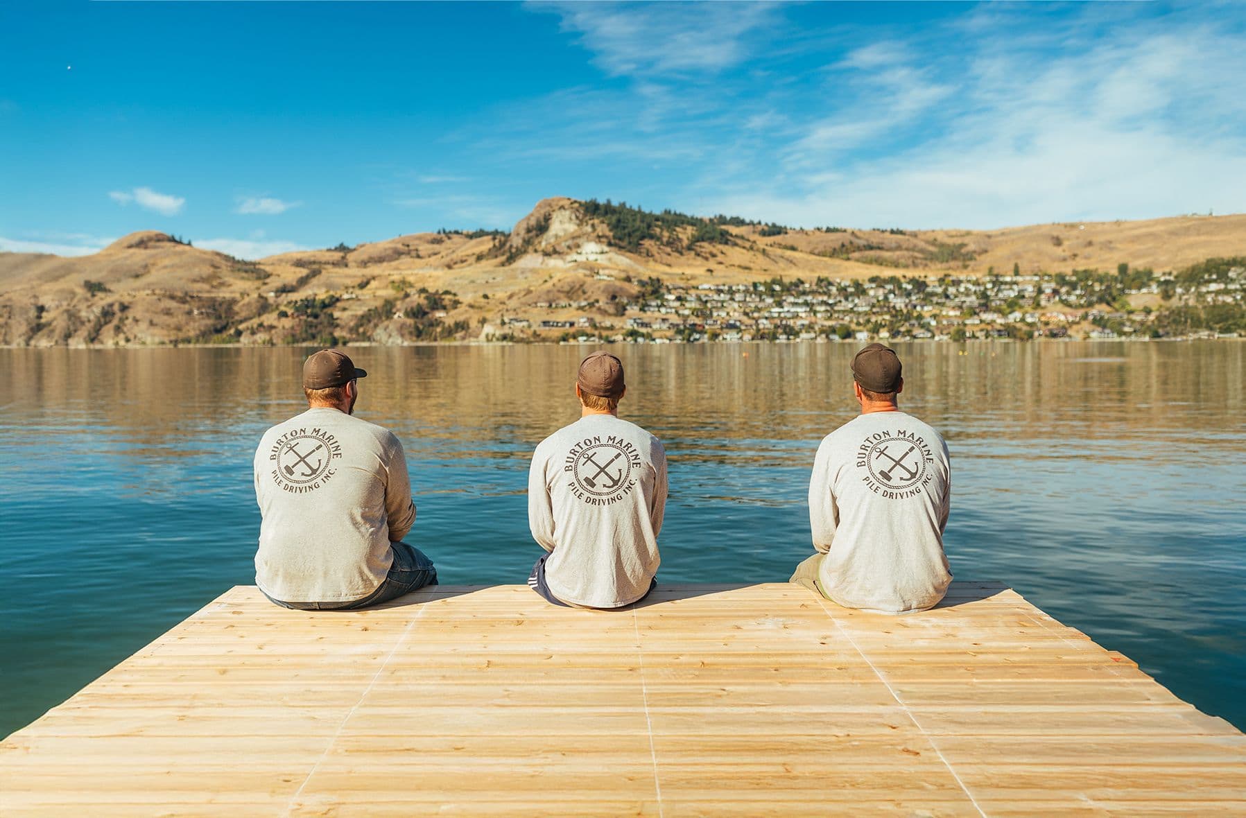 Burton Marine crew members sitting on a dock overlooking Okanagan Lake