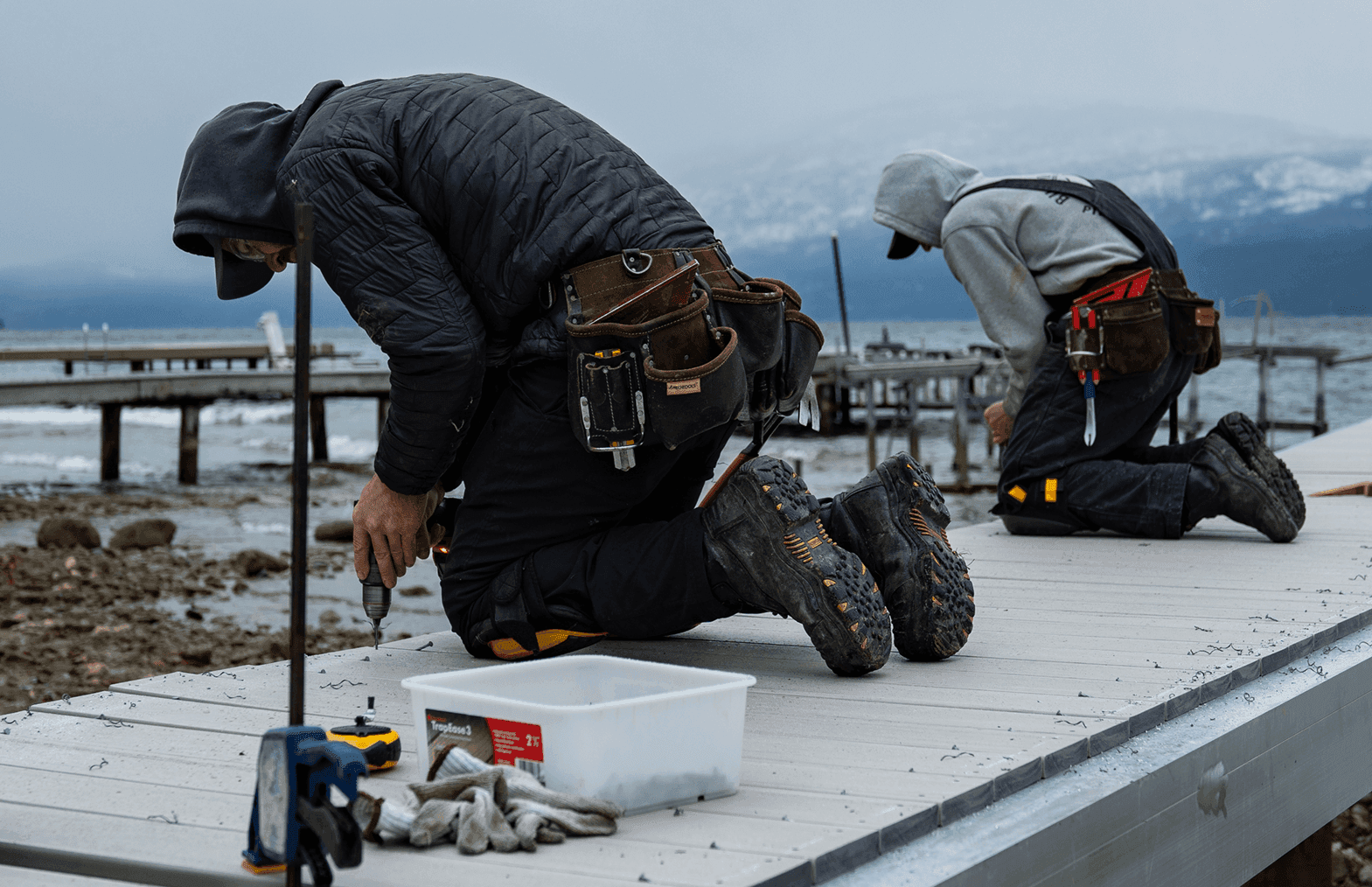 Two men working on a dock and upgrading the decking.