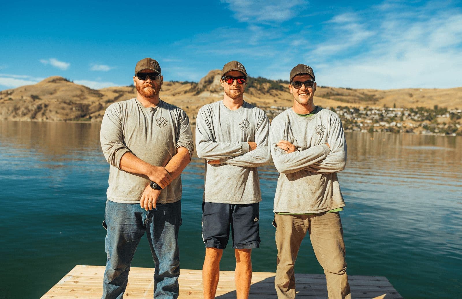 Three dock repair specialists standing together on a waterfront, representing the experienced marine construction team.