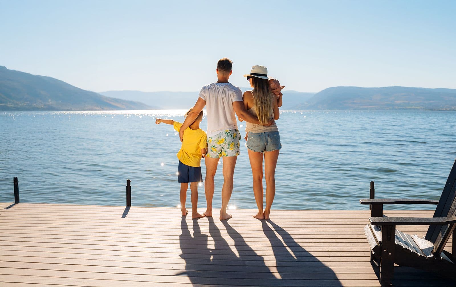 Family enjoying a sunny day on a lakeside dock in the Okanagan—showcasing the lifestyle benefits of custom residential dock features.