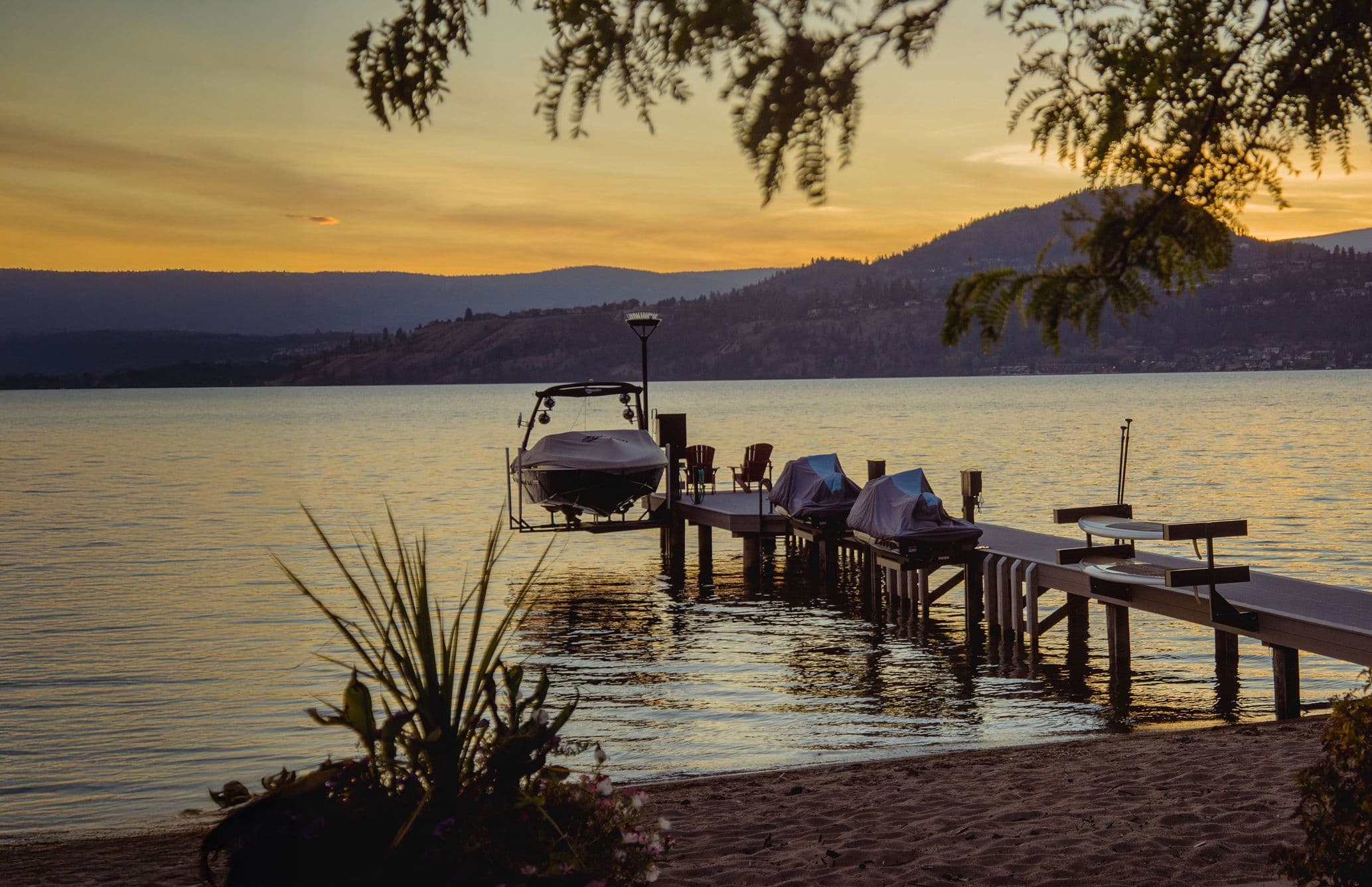 Lakeside residential dock at sunset with moored boats and covered PWC lifts, built for recreational and lifestyle enhancement