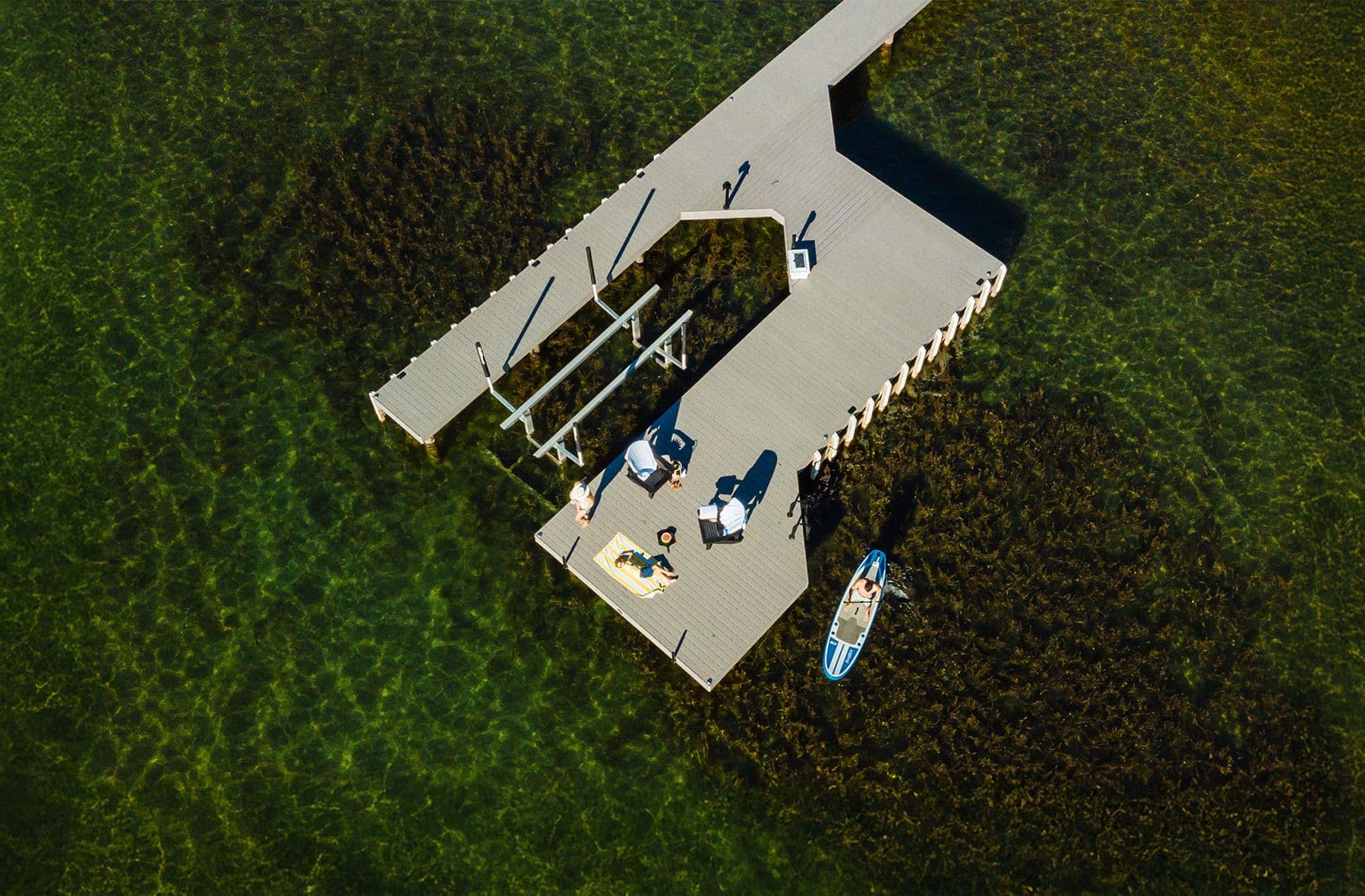 Overhead view of a custom-crafted dock with shaded lounging area and paddleboard access, built with expert carpentry