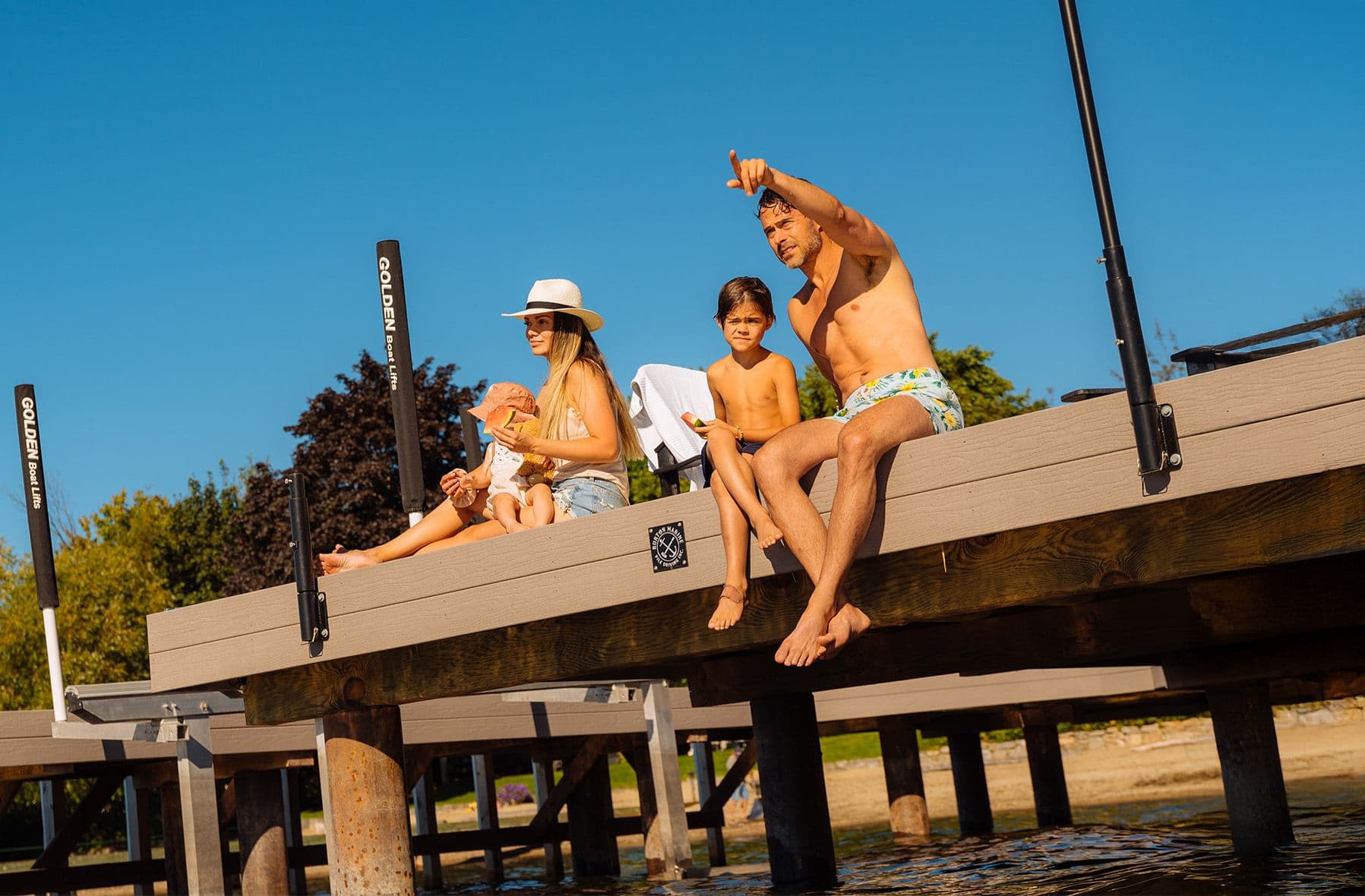 Family sitting on a dock enjoying the sunshine, symbolizing peace of mind from seamless federal, provincial, and municipal dock permitting.