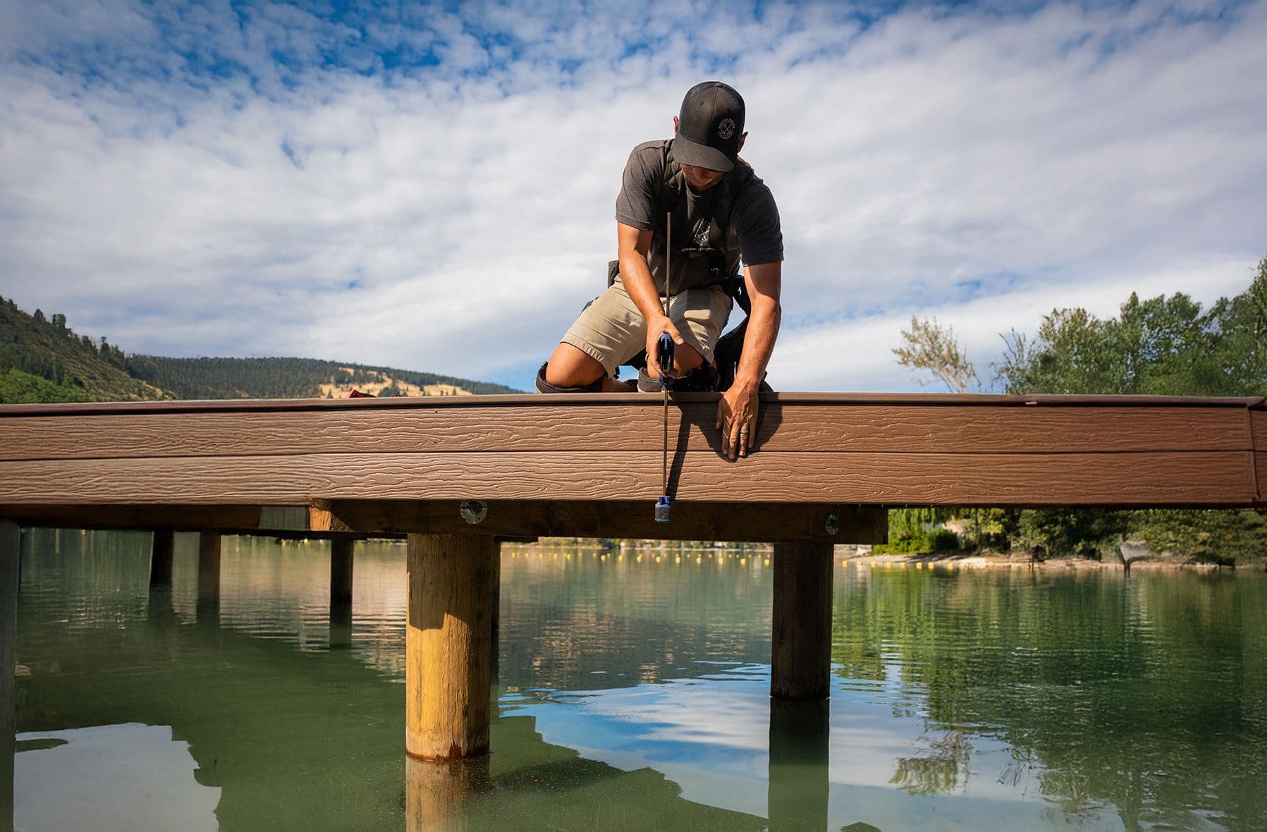 Dock builder fastening hardware during residential dock construction, showcasing hands-on experience, skilled craftsmanship, and attention to detail.
