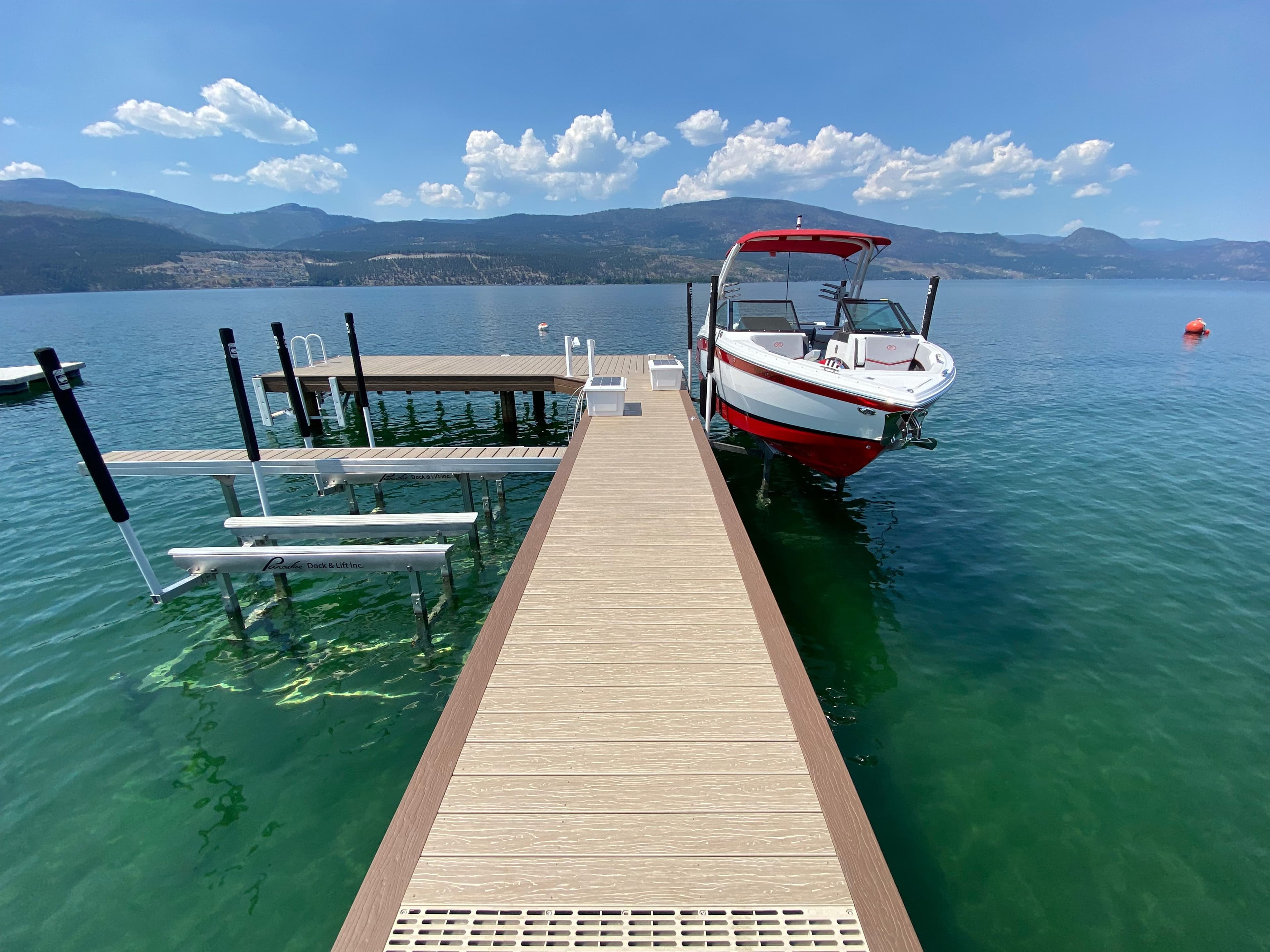 Fully rebuilt dock with composite decking, dual boat lifts, and moored watercraft on Okanagan Lake, offering upgraded safety, stability, and premium waterfront access.