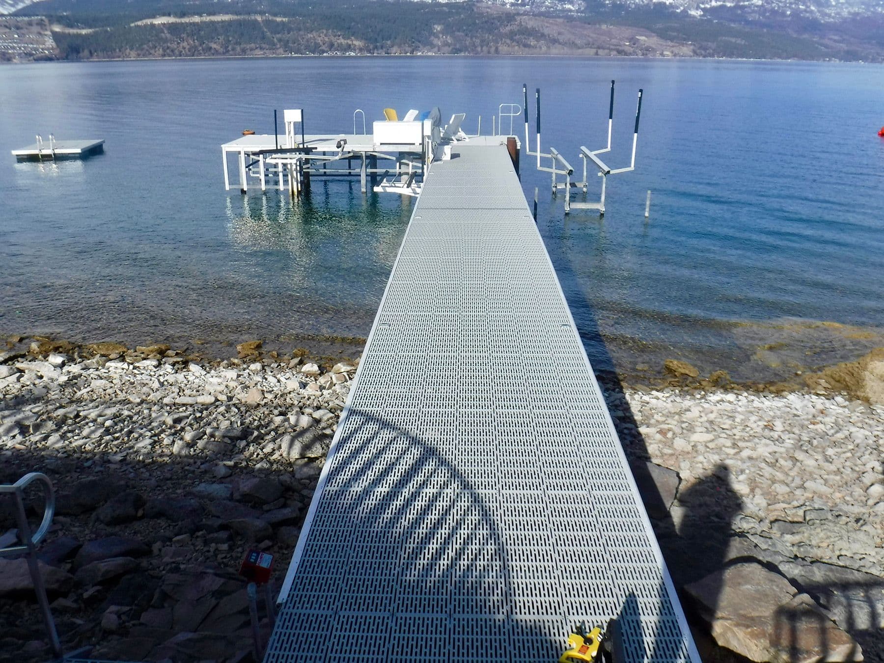 Old metal grate dock on Okanagan Lake with aging structure and exposed pilings, captured prior to full teardown and replacement with new dock system.
