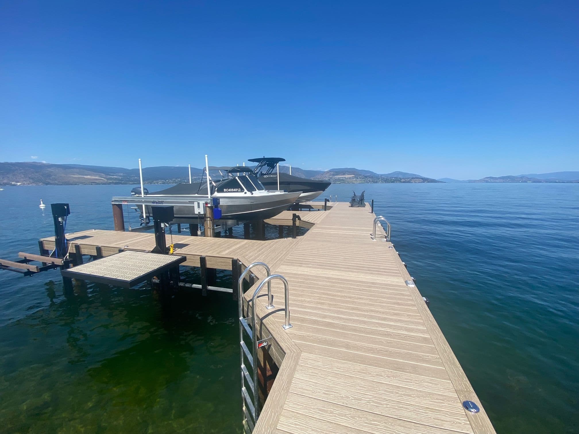 Newly installed residential dock in Kelowna with composite decking, dual boat lifts, and modern swim access, designed for durable, high-performance lakefront living.